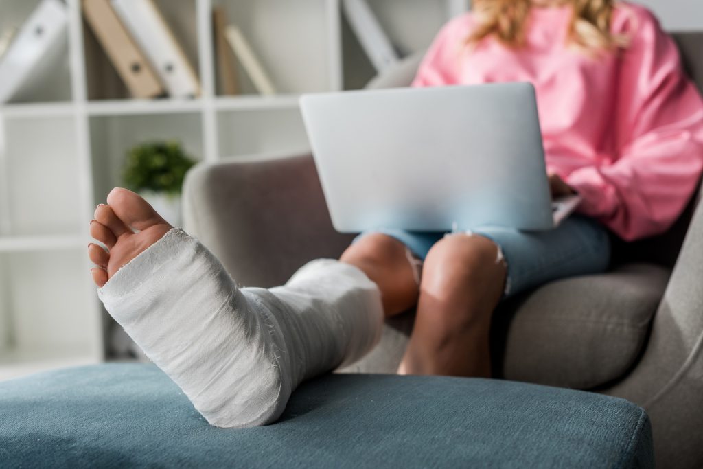 cropped view of injured woman working from home with laptop
